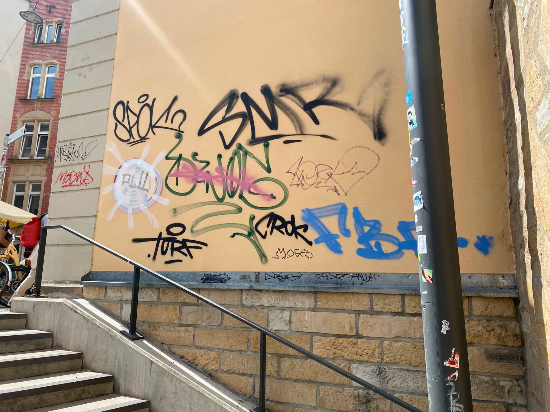 Beige Hausfassade mit mehreren großen Tags über einer Treppenanlage