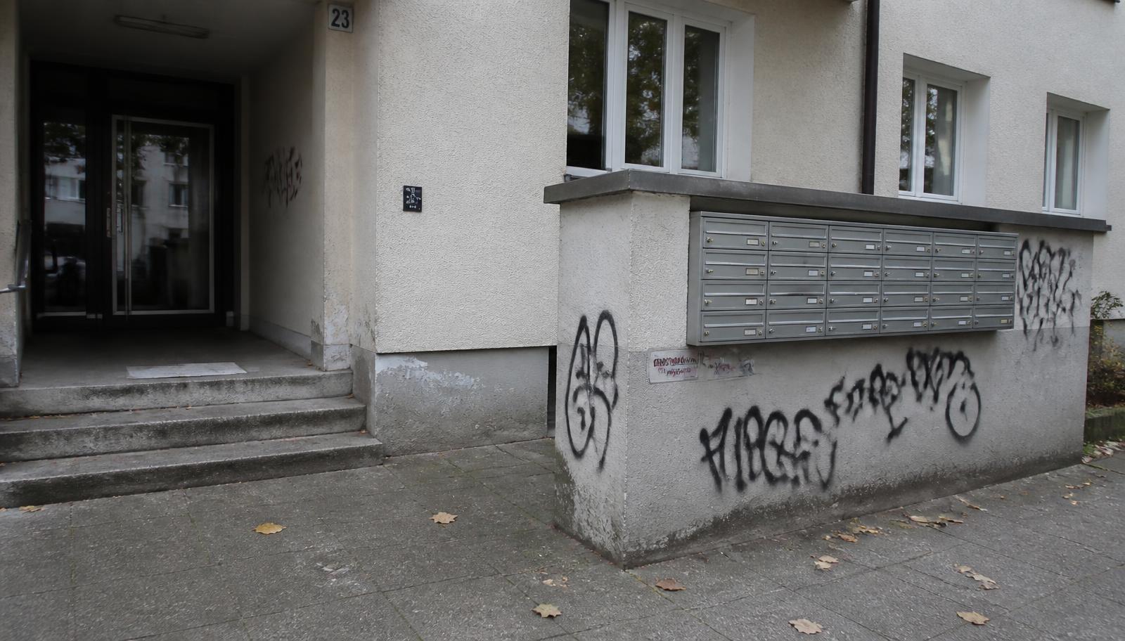 Hauseingang eines Mehrfamilienhauses mit Briefkastenanlage und schwarzen Tags auf dem Putzsockel