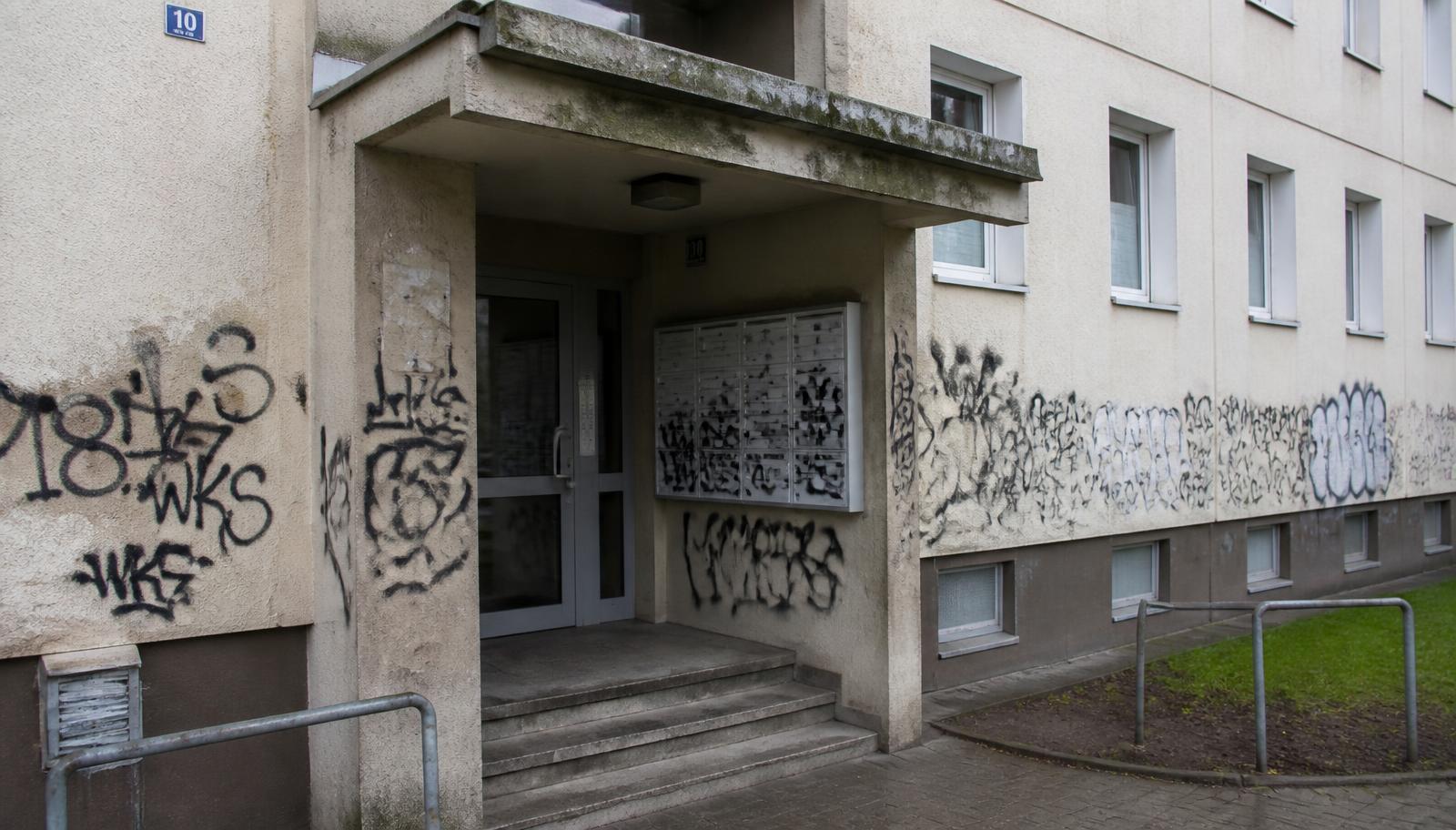 Hauseingang eines Wohnblocks mit Briefkastenanlage und schwarzen Tags im Sockelbereich