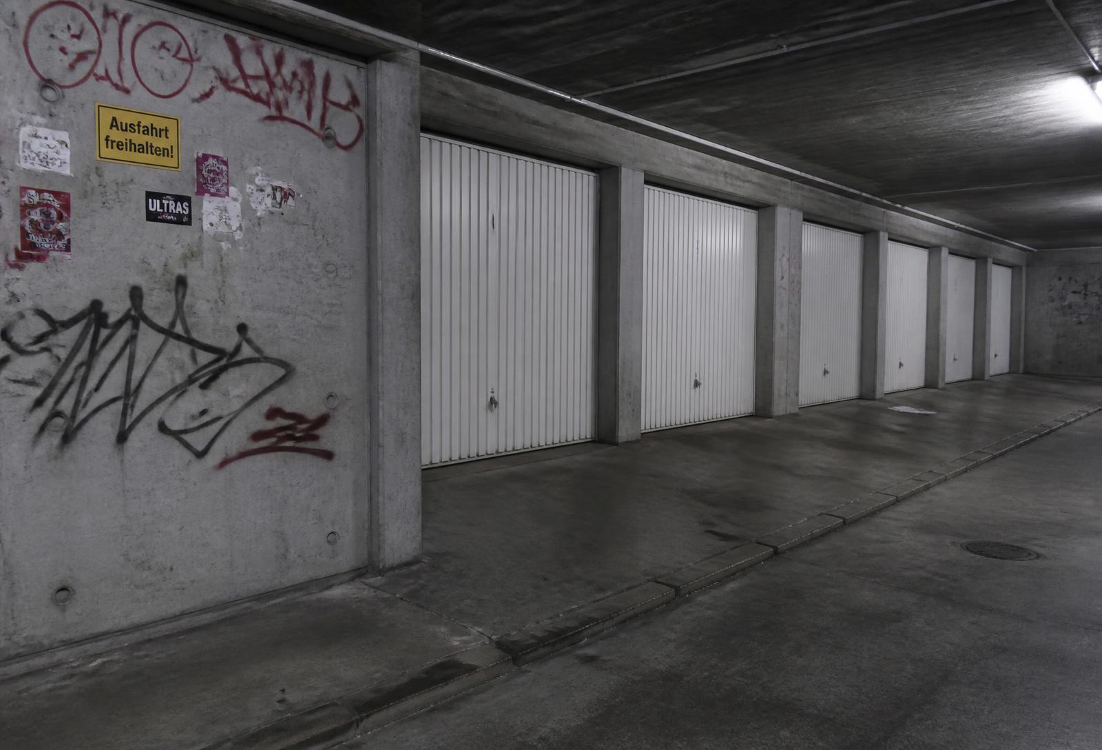 Garagenhof und Tiefgarage mit besprühten Betonwänden und Aufklebern
