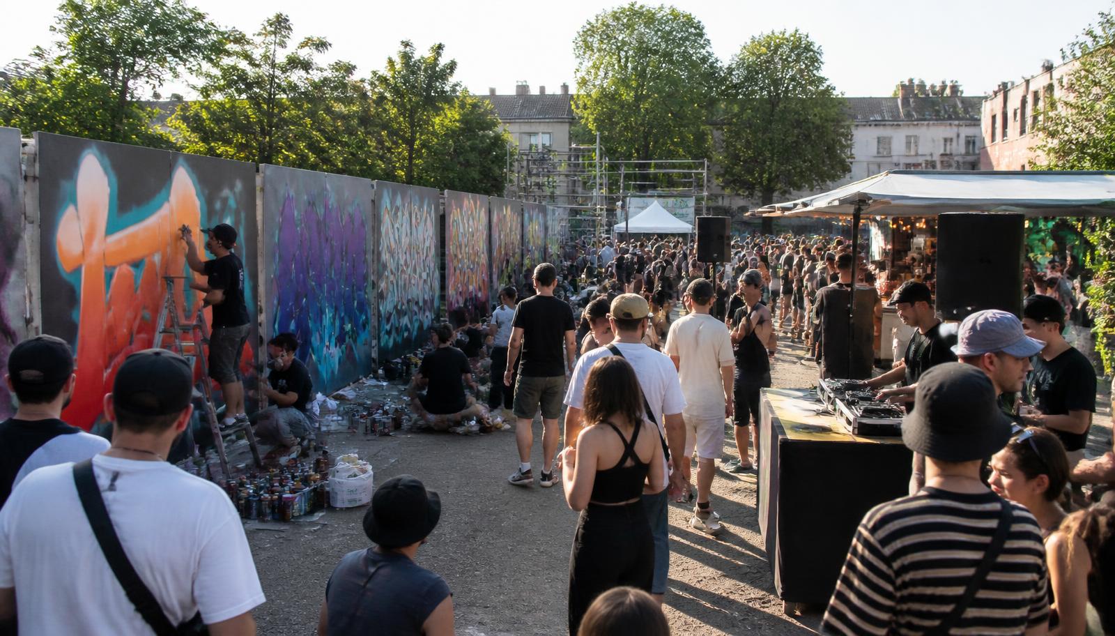 Graffiti-Jam mit Publikum, DJ-Pult und frisch bemalten Wandelementen